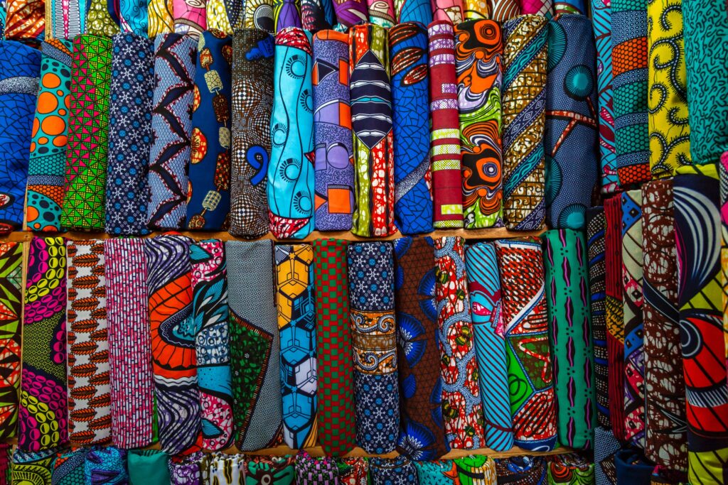 Vivid display of African wax print fabrics rolled and arranged side by side, showcasing an explosion of colors and patterns, a vibrant choice for Marseille souvenirs.