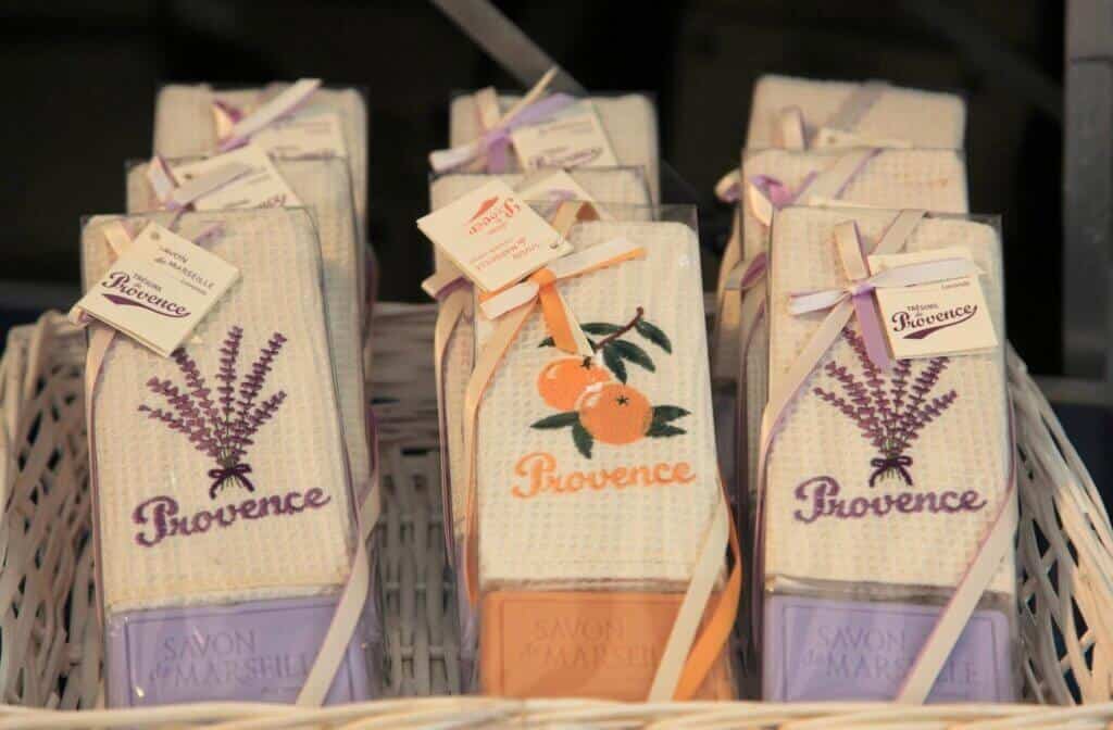 Elegantly packaged 'Savon de Marseille' soaps in a wicker basket, embroidered with lavender and orange designs and 'Provence', embodying the essence of the region and making for quintessential Marseille souvenirs.