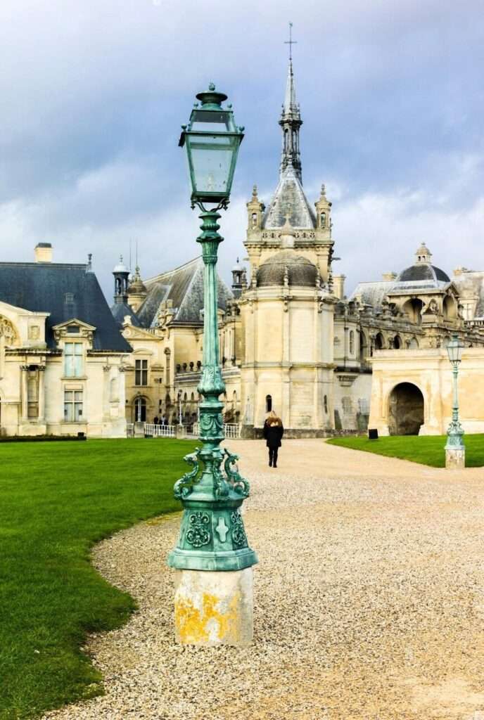 Lamp post and Palace of Chantilly in golden afternoon light - 14 Fantastic day trips from Paris.