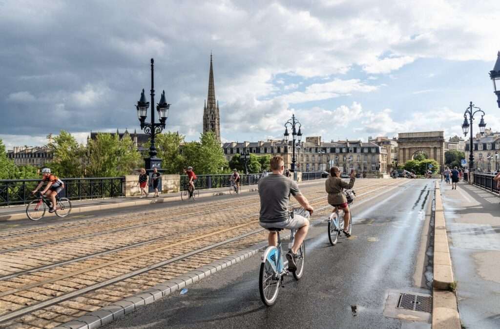 Bordeaux, France - August 2, 2022: Scenic view of Pont de Pierre Bridge with cyclists a rainy day of summer.