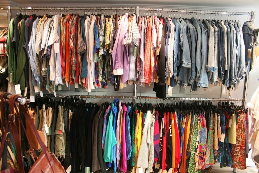 Vintage Shops in Paris: Densely packed clothing racks at Tilt Vintage Paris, filled with a varied selection of shirts, jackets, and skirts in multiple patterns and colors, showcasing the rich variety of retro styles available for fashion enthusiasts.