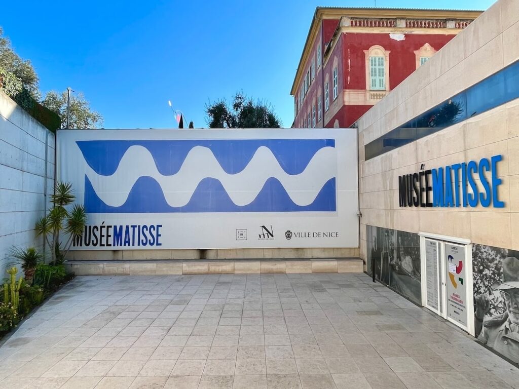 Entrance to the Musée Matisse in Nice, featuring a large sign with wavy blue patterns, inviting art enthusiasts to a cultural experience that can be enjoyed while visiting Nice in one day.