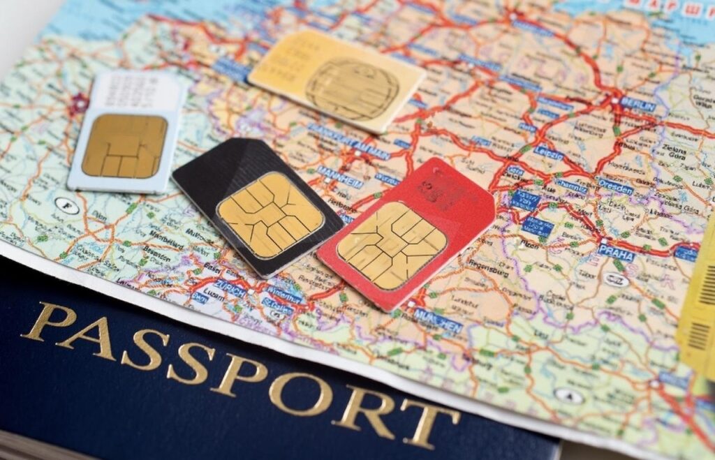Assorted SIM cards spread across a map of Europe, with one highlighted as a SIM card for France, placed near a navy blue passport, symbolizing the essentials for international travel to France.