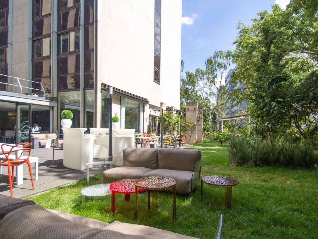 Tranquil hotel garden with lush greenery and a variety of modern outdoor seating options, offering a relaxed ambiance for guests to enjoy, nestled in the heart of Paris and complementing the experience of hotels with views of the Eiffel Tower.