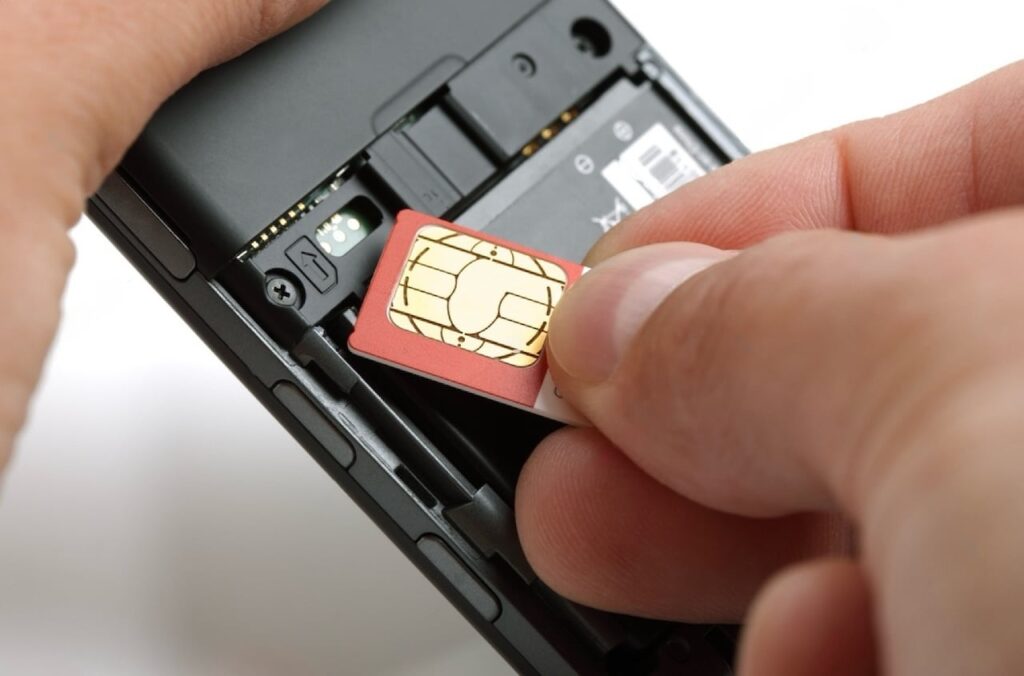 A hand is inserting a SIM card into a mobile phone, illustrating the process of installing SIM cards in France, suitable for travelers or residents needing connectivity on French networks.