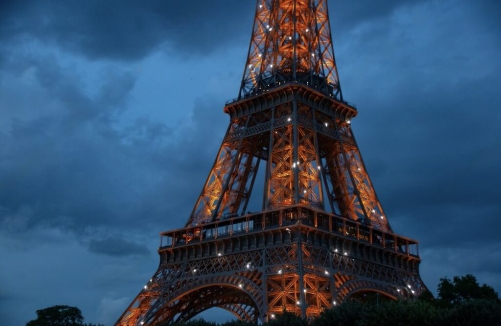 The illuminated Eiffel Tower at dusk, with its iron lattice glowing against the twilight sky, serves as a stunning backdrop for enthusiasts exploring Paris on motorcycle tours in France.