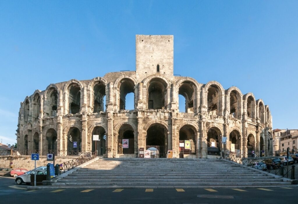 The ancient Arles Amphitheatre, a well-preserved Roman arena, under a clear blue sky, showcasing the architectural grandeur that makes it a highlight in the best cities in the South of France.