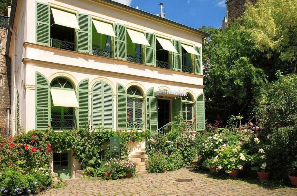 The charming entrance to the Musée de la Vie Romantique, nestled amidst lush greenery and vibrant flowers, a peaceful Parisian hideaway for couples to visit on Valentine's Day in Paris.