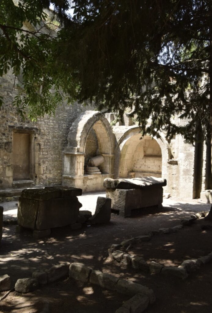 A serene walk through the ancient Les Alyscamps in Arles, lined with Roman sarcophagi and leading to a medieval church, a captivating journey through history and a top recommendation for things to do in Arles.