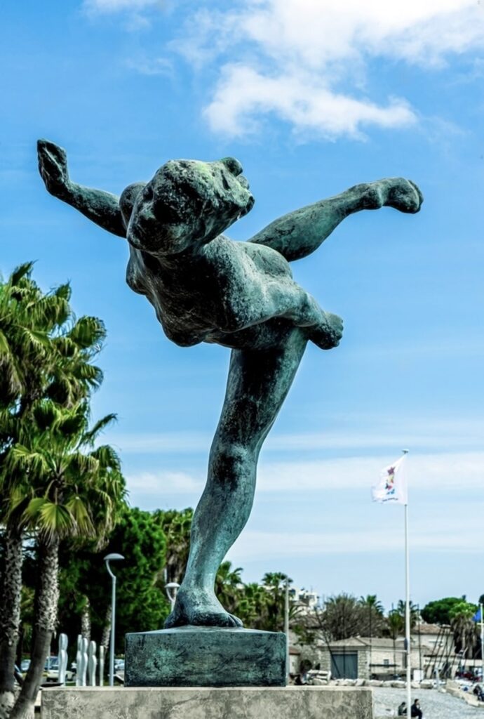 A dynamic bronze sculpture of a female athlete in a powerful pose set against the sky and palm trees in Cagnes-sur-Mer. This spirited artwork symbolizes the energy and culture of the city, a must-visit along the French Riviera with its vibrant artistic heritage.