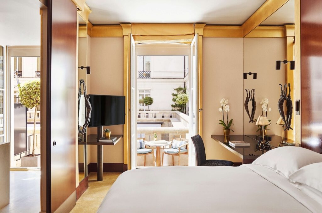 Elegant room at Park Hyatt Paris-Vendôme, one of the best 1st Arrondissement Paris hotels, featuring a luxurious bed, modern decor, and a private balcony with outdoor seating overlooking a charming courtyard.