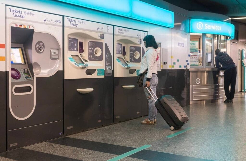 Traveler using a ticket machine at a Metro station, showing how to use the Metro in Paris for buying tickets with luggage in tow.