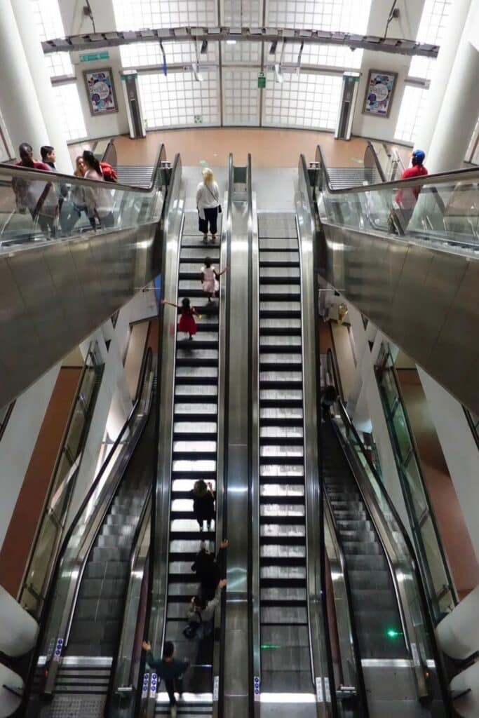 Passengers riding multiple escalators inside a Metro station, showing how to use the Metro in Paris for navigating large stations.