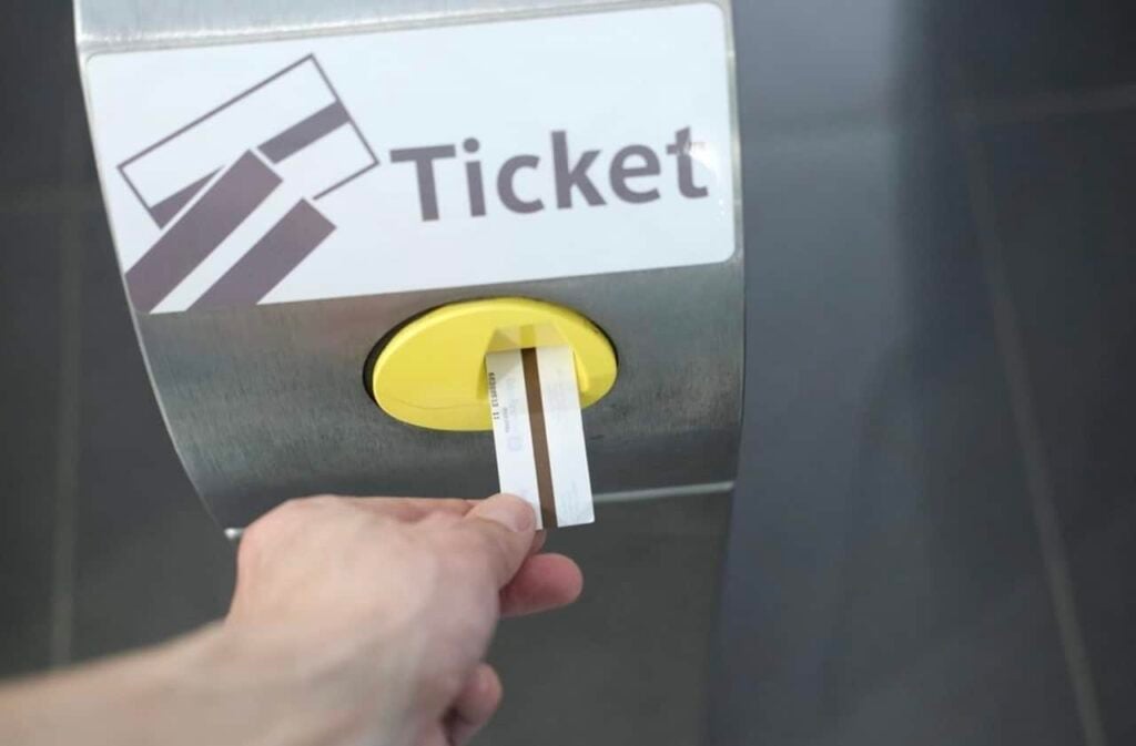 Inserting a paper Metro ticket into a turnstile, illustrating how to use the Metro in Paris with a standard t+ ticket.